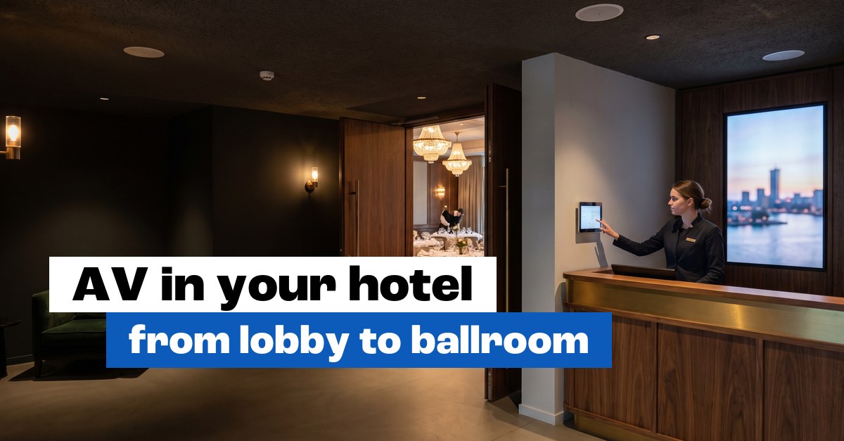 Receptionist using a wall panel in a hotel lobby with a digital signage screen and a view of the function room